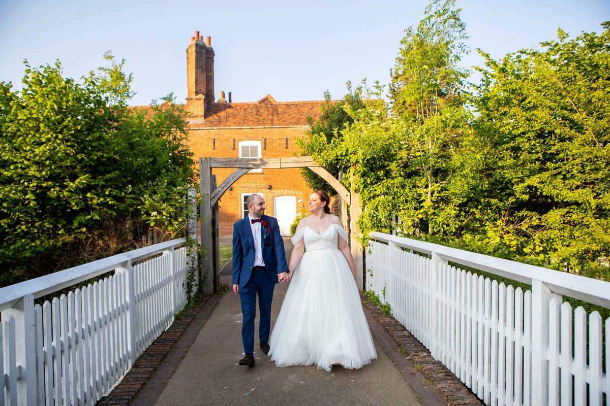 Wedding couple walking through a green field with wedding guests following behind