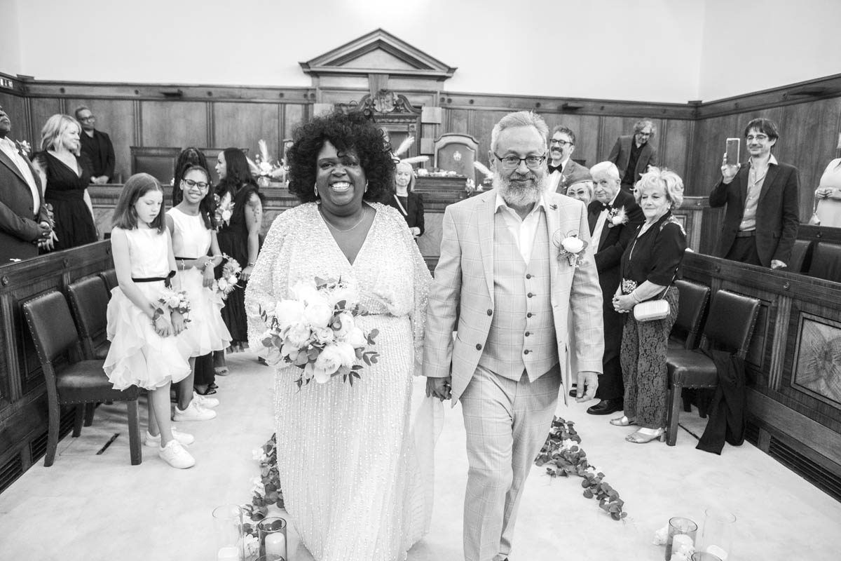 Wedding ceremony kiss with guests applauding in the background